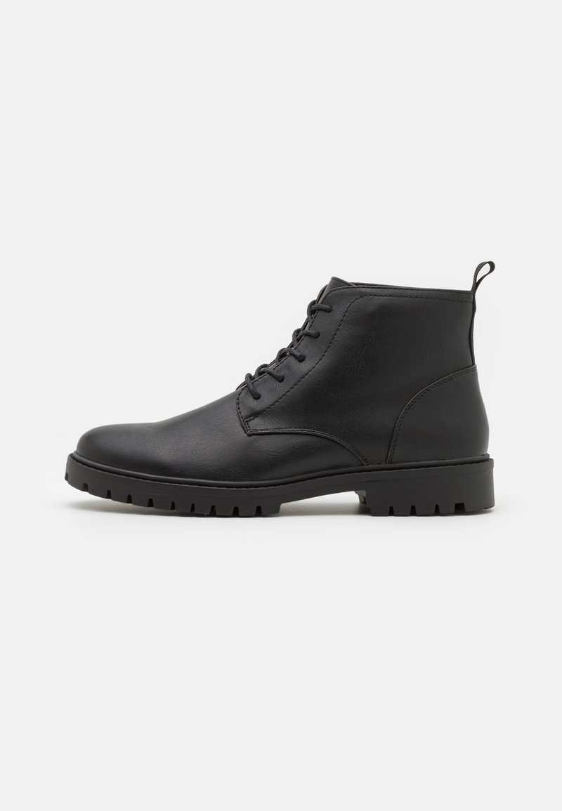 Botas de tornozelo em couro preto com atacadores na parte da frente, bico arredondado e sola de borracha robusta. Possui uma alça na parte de trás para facilitar o calçar.