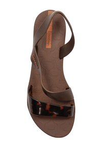 Sandali piatti marroni con una suola texturizzata, caratterizzati da due cinturini: uno in plastica effetto tartaruga e uno in un materiale marrone flessibile.