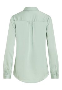 Blouse vert clair à manches longues avec empiècement dans le dos, pli central, poignets boutonnés et ourlet arrondi, vue de dos.