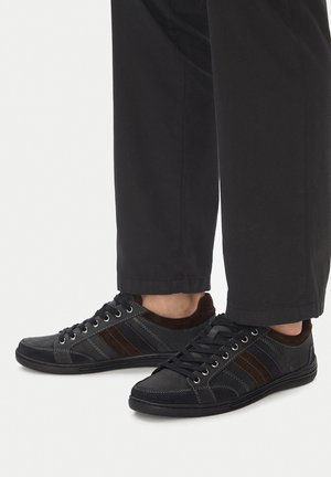 Czarne i brązowe trampki wykonane z połączenia skóry i zamszu, z trzema poziomymi paskami i metalowymi oczkami na sznurowadła.