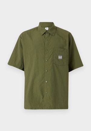 Kurzarmhemd aus olivgrünen Stoff mit einem Button-Down-Kragen, ausgestattet mit einer Brusttasche, die ein graues GAP-Logo-Patch zeigt.