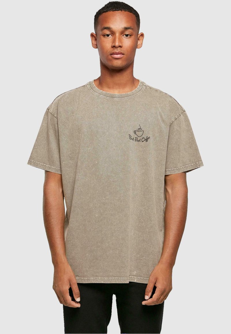 Beżowy, oversize t-shirt z bawełny, z okrągłym dekoltem, krótkimi rękawami i nadrukiem "Ale najpierw kawa" na lewej piersi.