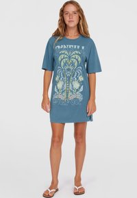 Niebieska bawełniana sukienka t-shirtowa z krótkimi rękawami, z du�żą kwiatową grafiką w kolorze żółtym i zielonym. Po bokach rozcięcia i luźny krój.