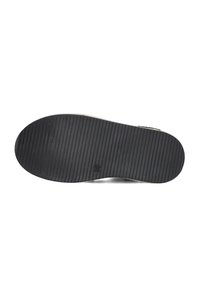 Zwarte rubberen schoenenzool met diepe horizontale groeven voor grip, met een ronde vorm en een klein reliëflogo nabij de hiel.