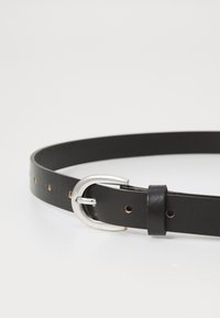 Ceinture en cuir noir avec une boucle en métal argenté, dotée de petits trous le long de la sangle pour un ajustement facile et une texture lisse.
