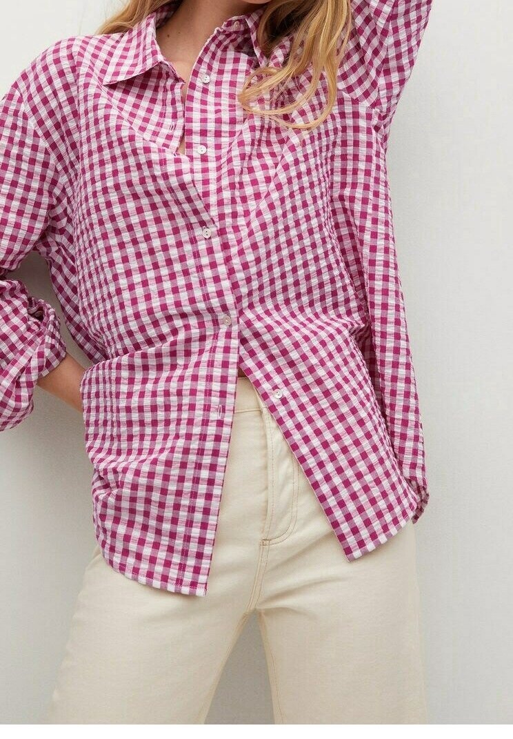 Camisa de cuadros en rosa y blanco, con diseño de botones y cuello, de manga larga y corte relajado, combinada con unos vaqueros color crema.
