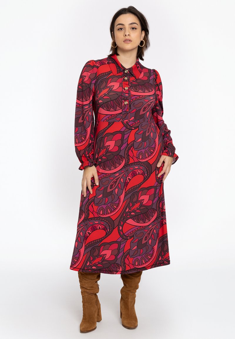 Langärmliges Kleid im roten und lila Paisleymuster, mit einem Kragen und Knopfdetails. Hergestellt aus glattem Stoff, endet unter dem Knie.