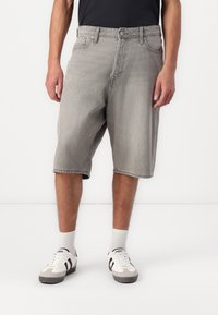 Pantalones cortos de mezclilla gris con un ajuste relajado, longitud a medio muslo, diseño de cinco bolsillos y detalles de costura sutiles, combinados con zapatillas blancas.