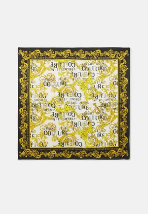 Pañuelo cuadrado de seda con elaborados patrones florales barrocos amarillos sobre un centro blanco y un borde negro, con el texto repetido "Versace Jeans Couture".