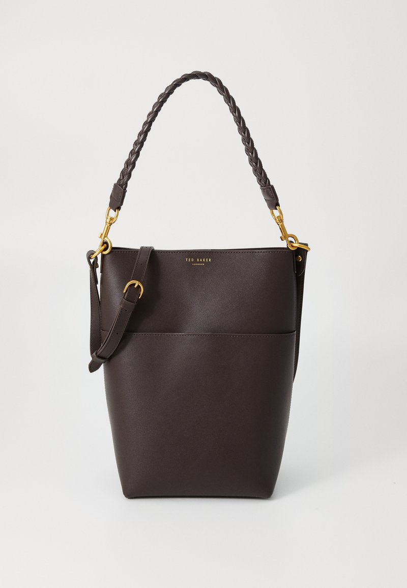 Mala de balde em pele castanha com uma alça trançada e detalhes em metal dourado. Apresenta uma textura suave e um bolso frontal horizontal.