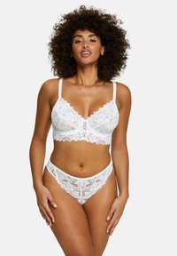 Bralette en dentelle blanche avec des motifs floraux et des bords festonnés, associé à un string en dentelle assorti. Dispose de bretelles ajustables et d'une texture douce.