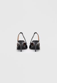 Melna lakota ādas slingback zābaki ar smailu purngalu un plānu stiletto papēdi, kas raksturojas ar gludu tekstūru un minimālistisku dizainu.