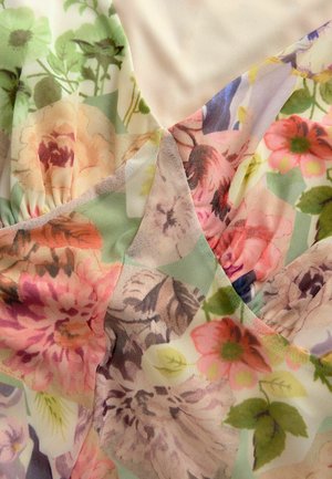 Tessuto floreale caratterizzato da un mix di colori pastello tenui, tra cui tonalità di rosa, verde e viola, con vari motivi floreali e una texture fluida.
