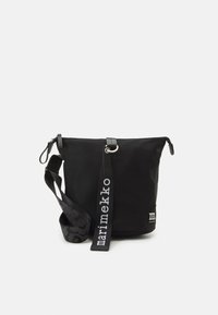Black nylon shoulder bag with a zip closure, textured strap featuring a pattern, and logo label on the front. Adjustable strap included.