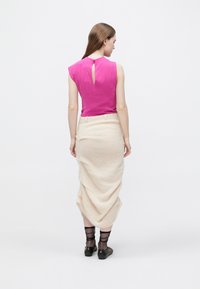 Fuchsiový top bez rukávů s detailem průsvitného otvoru na zádech, doplněný krémovou plisovanou sukní a průhlednými černými kotníkovými ponožkami a balerínami.