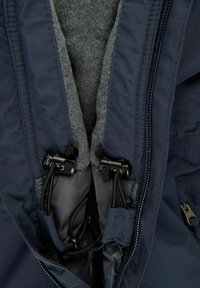 Insidan av marinblå jacka med grå fleecefoder, utrustad med justerbara svarta kordellås och blixtlås längs den främre öppningen. Mjukt textur.