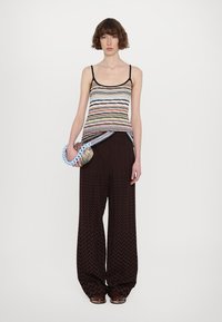 Striped tank top with thin black straps, paired with wide maroon pants featuring a zigzag pattern. Accessory: chunky blue chain handbag.