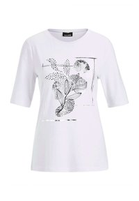 Weißes T-Shirt mit kurzen Ärmeln, das ein schwarzes florales Design mit gepunkteten Akzenten und metallisch silbernen Linien zeigt. Weicher, glatter Stoff.