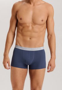 Marinblå kalsonger i mjukt tyg med en grå midjeband med "HANRO"-logotyp, tät passform och minimala sömmar för komfort.