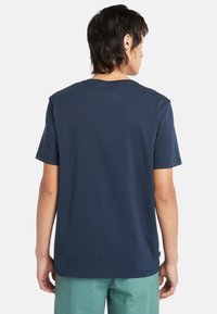 Camiseta de manga corta azul marino con cuello redondo. Tela suave y corte relajado. Presenta un dobladillo plano y una marca mínima cerca de la parte inferior.