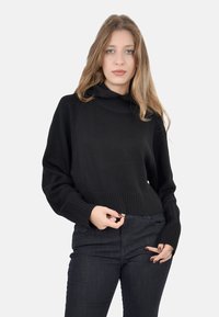 Maglione nero lavorato a maglia con collettino alto e polsini a costine. Il design è corto e presenta un motivo testurizzato lungo le maniche.