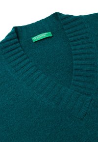Maglione teal a scollo a V con texture a coste col colletto e all'orlo. L'etichetta riporta "United Colors of Benetton" in verde all'interno.