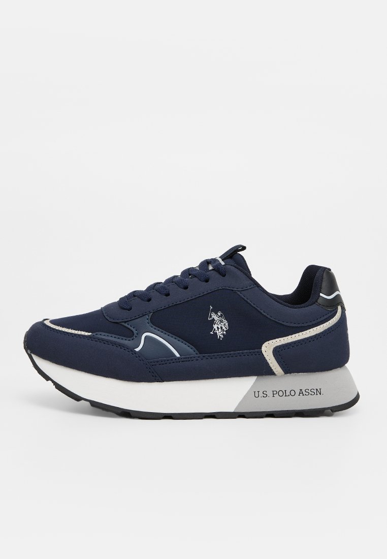 Zapatilla deportiva de color navy con parte superior sintética, diseño con cordones y suela blanca. Presenta un logo en el lateral y costuras de acento en gris y crema.