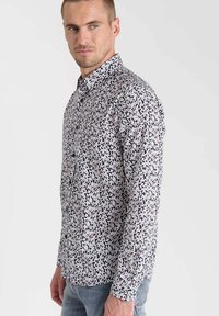 Chemise à boutons florale avec un fond noir et des motifs de feuilles blanches, roses et bleues. Manches longues et design de col classique.