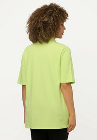 T-shirt a maniche corte di un luminoso verde lime, realizzato in tessuto morbido con una vestibilità rilassata. Presenta un design semplice con orlo dritto.