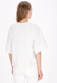 Grijs, cropped sweatshirt met korte raglanmouwen en een ronde hals. Zachte textuur en een eenvoudig ontwerp. Geen zichtbare patronen of accenten.