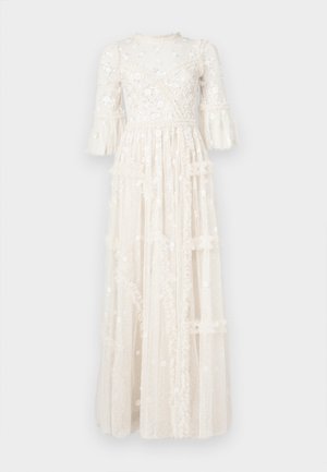 Μακρύ ελεφαντόδοντο φόρεμα από διαφανές ύφασμα με κεντήματα λουλουδιών, φουσκωτά μανίκια, πινελιές με βολάν και φούστα με στρώσεις.