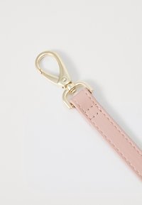 Różowy skórzany pasek z złotym metalowym zapięciem i detalami szycia, charakteryzujący się gładką fakturą i pętlą na końcu do mocowania.