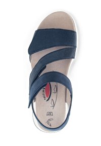 Navy sandal with soft textured straps, wide design, cushioned footbed, and a white sole. Features a brand logo on the insole.