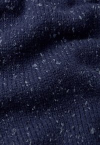 Tissu tricoté bleu marine présentant un motif texturé avec des éclats clairs, mettant en valeur une apparence douce et superposée ainsi que des détails côtelés tout au long.