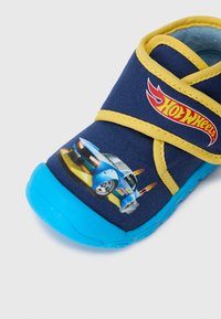 Morska kanwa butów z żółtymi paskami, niebieską gumową podeszwą i grafiką samochodu Hot Wheels z boku, z kolorowymi płomieniami i akcentami.