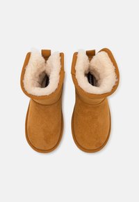 Bottines en daim marron avec une doublure en shearling crème douce et une surface texturée. Comprend des coutures piquées et des languettes à l'arrière.