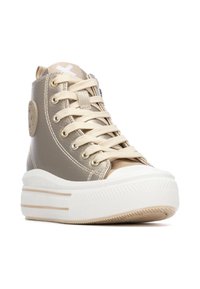 Zapatillas altas con un upper sintético metálico beige, puntera redonda, cordones crema y una suela de goma blanca con acentos texturizados.