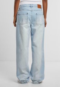 Ljusblå denimjeans med en avslappnad passform, som har två bakfickor, logopatch på midjan och subtil blekning vid benen.