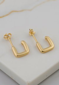 Guld färgade hoopörhängen med en slät, rundad fyrkantig form. Tillverkade av metall, med en stift-bakdel och blank yta.