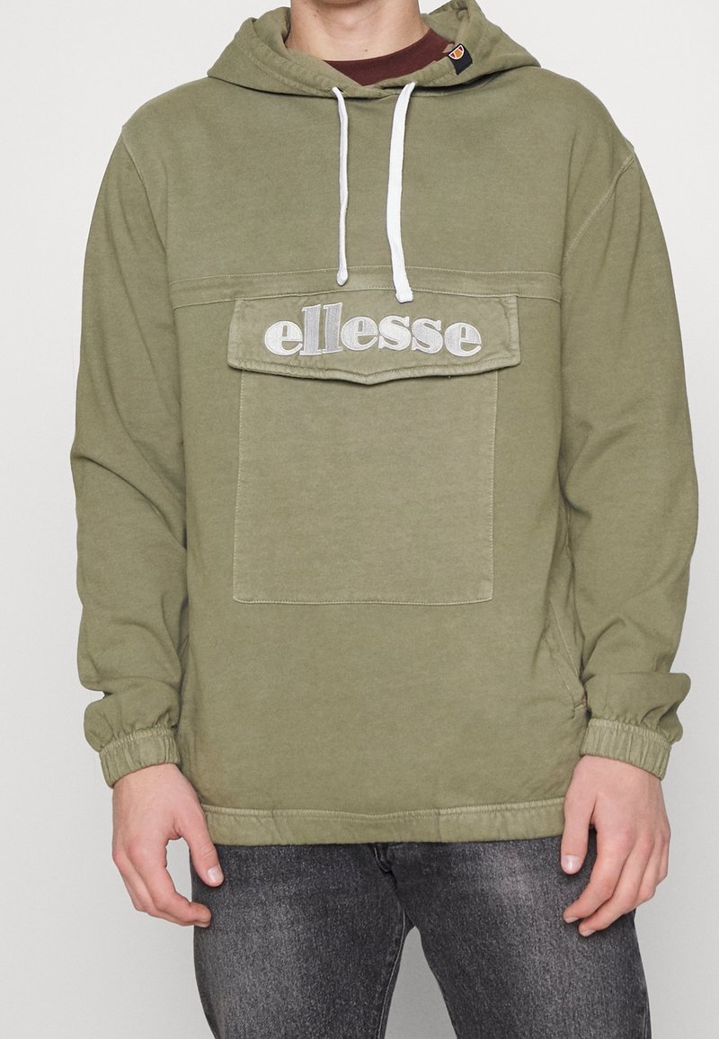 Sudadera de color verde oliva con cordones blancos, bolsillo tipo canguro y logotipo bordado de "ellesse" en el pecho. Presenta puños y dobladillo elásticos.