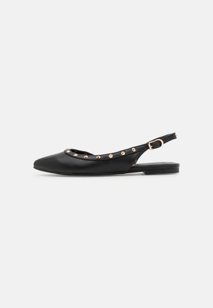 Chaussure plate slingback noire avec bout pointu et clous ronds dorés le long du bord supérieur et une bride réglable avec boucle.