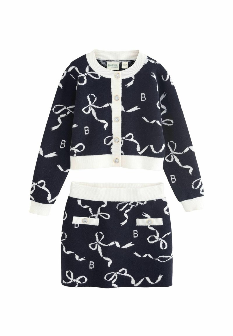 Set di maglina blu navy composto da due pezzi con motivi a fiocco bianchi. Il cardigan presenta un colletto rotondo e bottoni; la gonna ha una vita alta e tasche decorative.