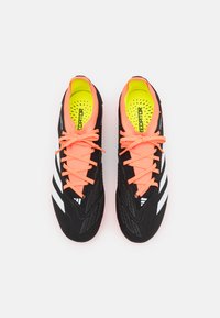 Scarpe sportive nere con lacci arancioni brillanti, caratterizzate da una tomaia texturizzata, tre strisce bianche e una soletta verde neon con perforazioni.