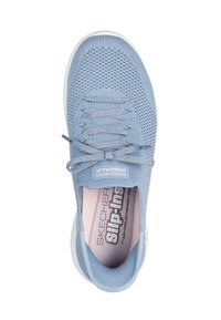 Zapatilla azul claro de malla sin cordones, con punta redonda, parte superior tejida, diseño texturizado, cuello acolchado y suela de goma blanca.