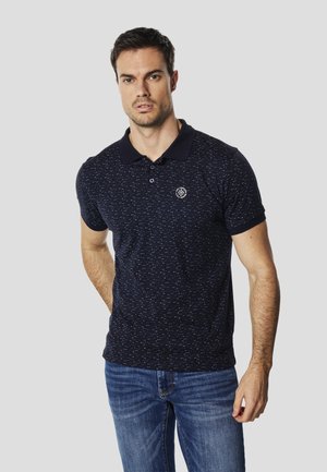 Polo azul marino hecho de tela texturada, con un diseño estampado, cuello abotonado y un pequeño logo bordado en el pecho.