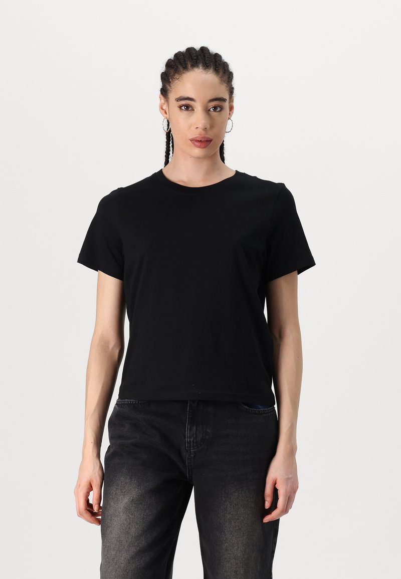 Sort kortærmet t-shirt lavet af blødt bomuld. Har en klassisk rund hals og en afslappet pasform. Bæres sammen med mørkegrå jeans.
