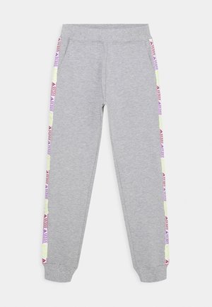 Jasnoszare spodnie dresowe z elastycznymi mankietami i pasem, ozdobione bocznymi paskami z powtarzającymi się czerwono-fioletowymi napisami "GUESS".