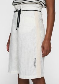 Linnenblend rok in off-white met een beige zijstreep. Voorzien van een elastische tailleband en een trekkoord, met een logo nabij de zoom.
