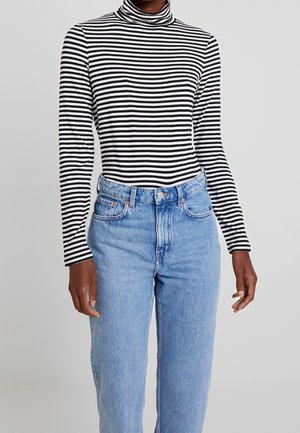 Maglione a rete a righe bianche e nere con maniche lunghe abbinato a jeans chiari a vita alta. Caratterizzato da un tessuto morbido e una vestibilità comoda.