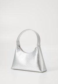 Sac à main argenté, texturé, avec une poignée courbée, de forme triangulaire, fermeture zippée et une surface métallique brillante.